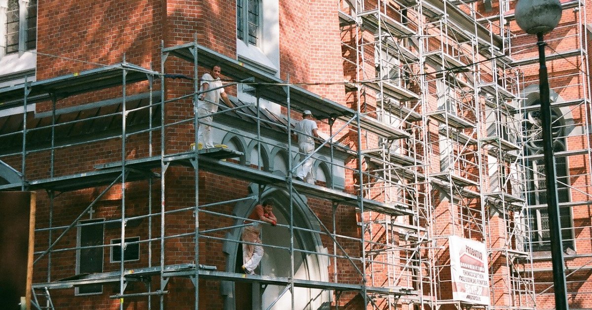 Werklieden op steigers tijdens de verbouwing van een bakstenen gebouw